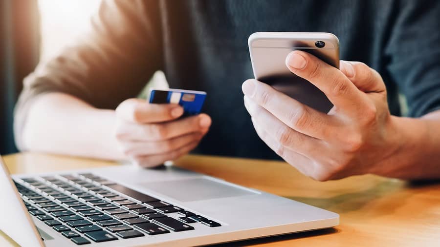 Person holding a credit card in front of a laptop